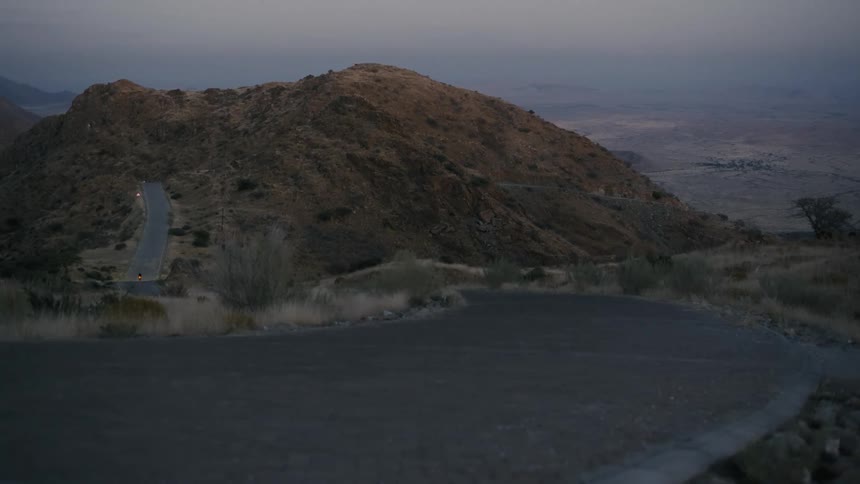 Man riding a bicycle on a narrow street going down through the mountains on a morning