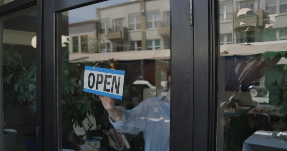 A female employee turns a closed sign around in a restaurant