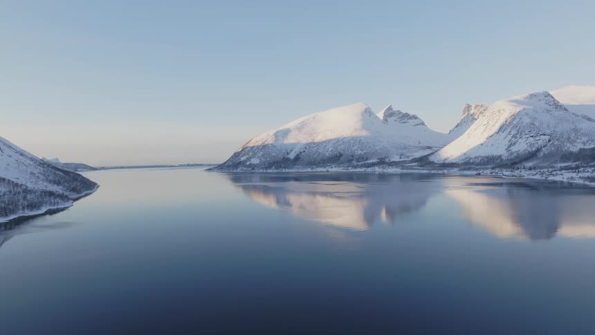 Some mountains covered in ice reflecting their image in the water of a still lake