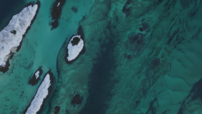 Several snow and ice covered islands in an ocean