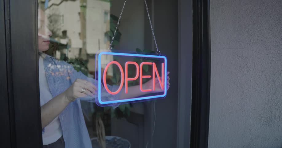 An employee at a store adjusts the open sign on the door