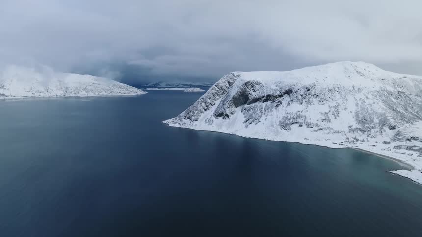 The mountains by the shore are covered with ice and snow