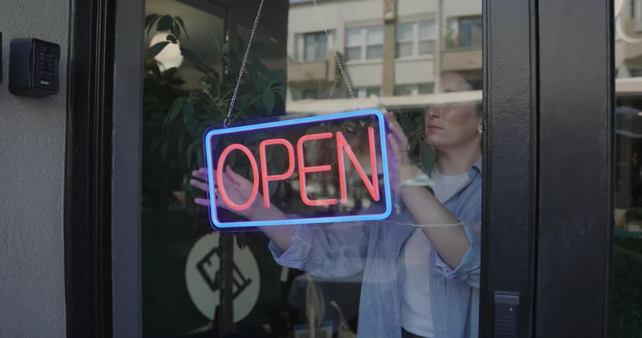 A woman turns on the open sign in the restaurant