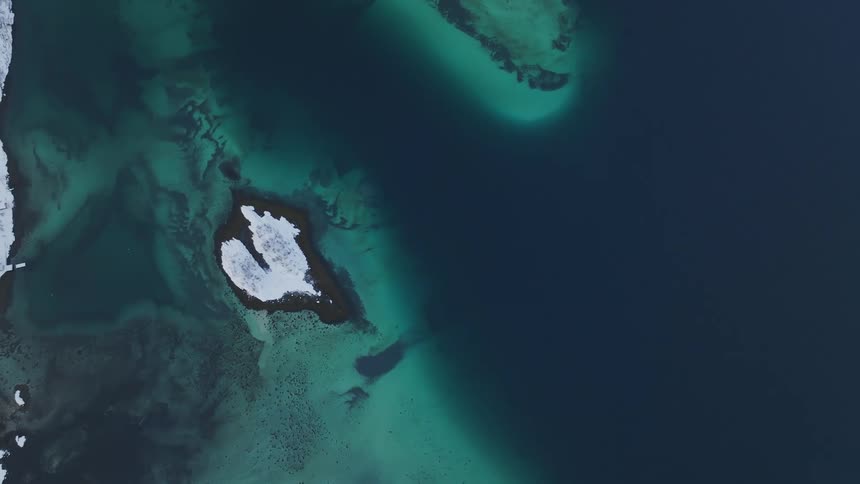 A partially snow covered island near a coast