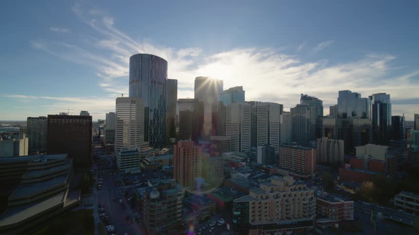 An aerial dolly out movement of a downtown metropolis at day with sun flare