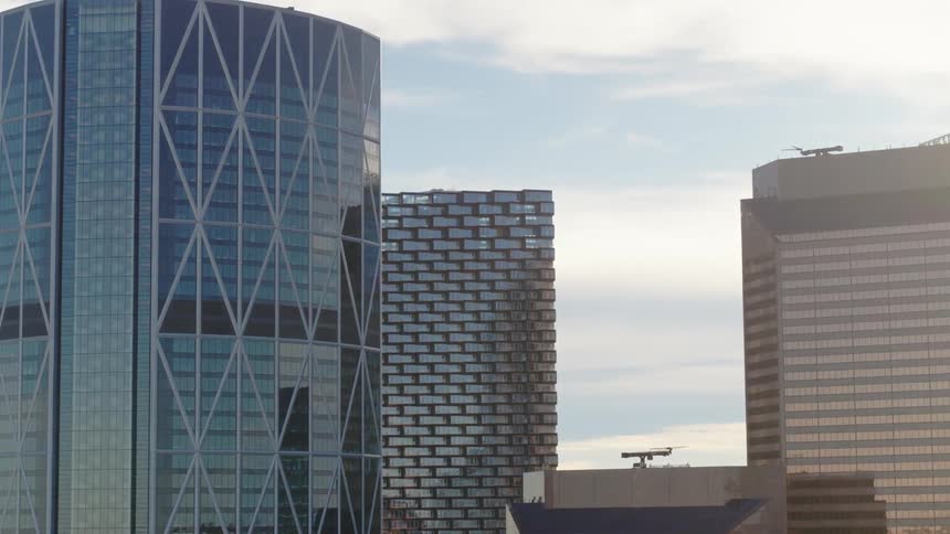 Several large towers in a city downtown with the sun shining behind