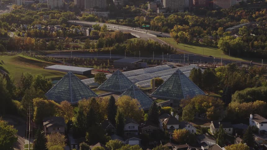 Aerial panorama of greenhouses in glass pyramids next to a residential neighborhood