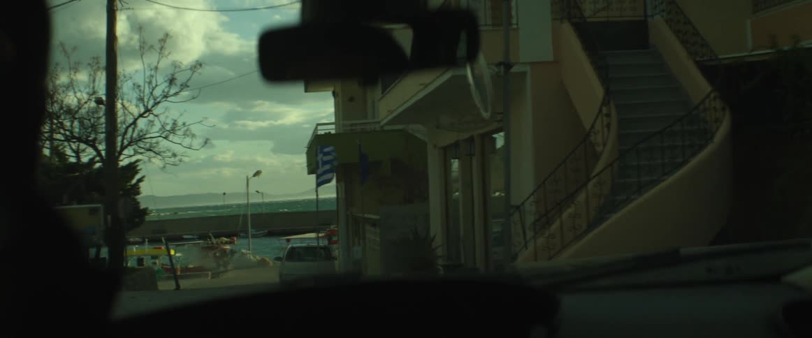 Person driving down a road by the water on a cloudy day