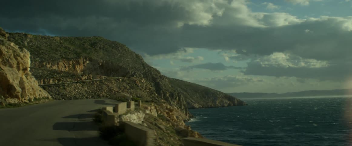 A vehicle drives on a coastal road