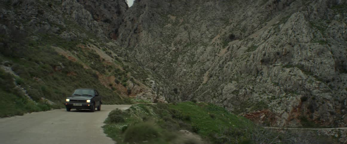 Black car driving along a road through the mountains
