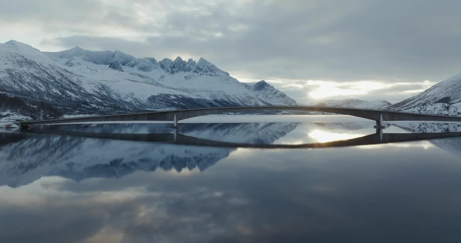 Aerial view of a bridge over a lake in the mountains at sunset