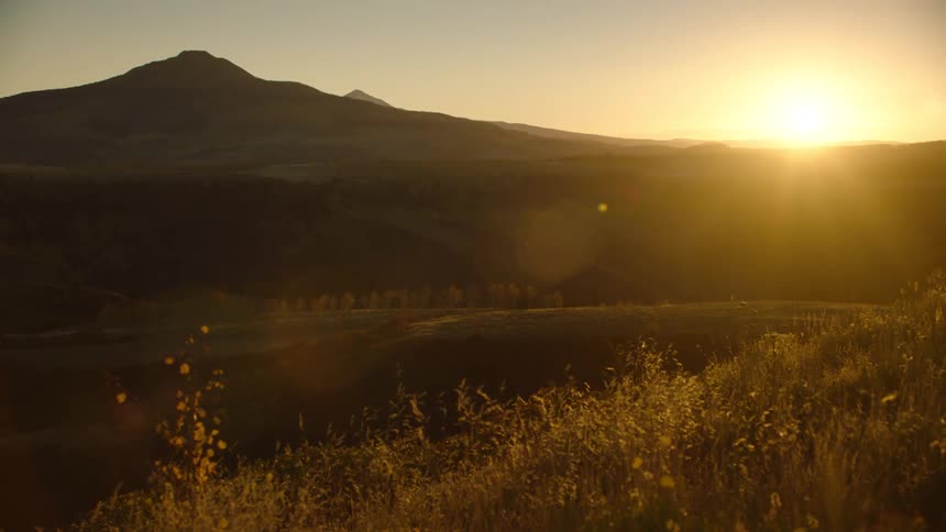Landscape of a field with mountains and sunset in the background
