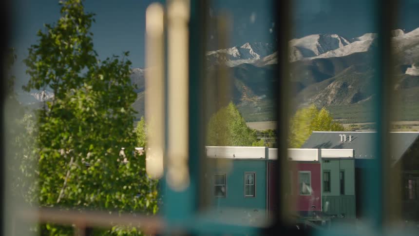 A view of a small town next to a mountain range through a window