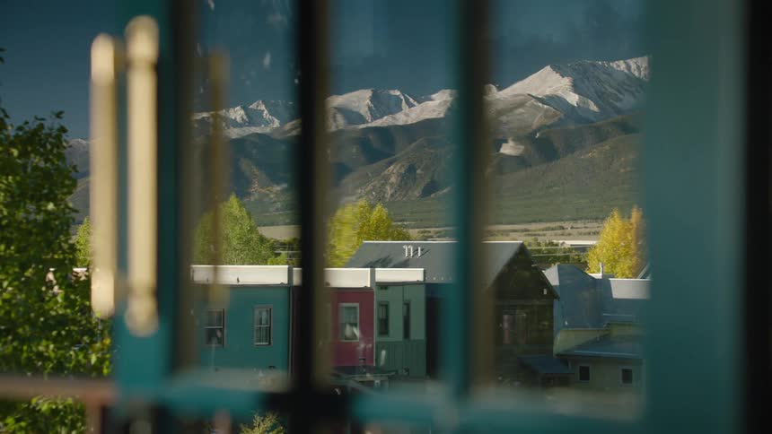 Some houses in a rural region and in the background a mountain range with some covered in snow