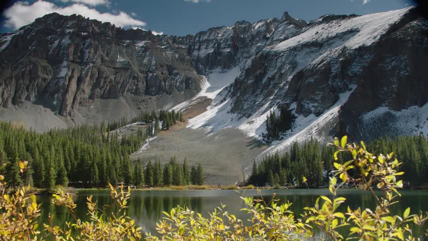 Landscape of a greenish lake with snowy mountain ranges in the background
