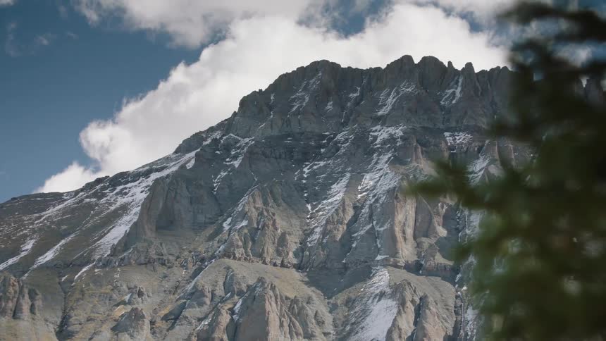 A panoramic view of a mountain range with peaks partially covered in snow