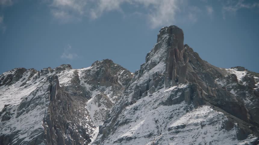 A snowcapped mountain peak under a blue sky with clouds