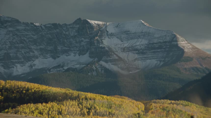 A mountain with a snowcovered peak stands against a overcast sky