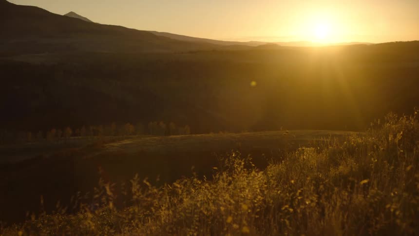 The sun is setting in the distance behind the mountains in the horizon