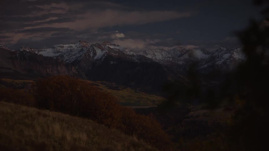 Natural landscape of wooded hills and mountains with snow on a dark sky day