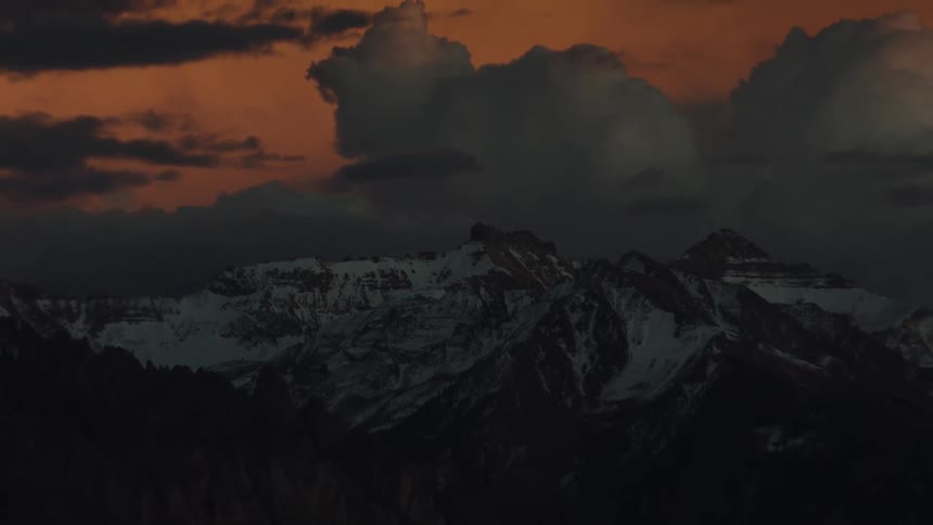 A mountain range under a dramatic orange sky at dusk