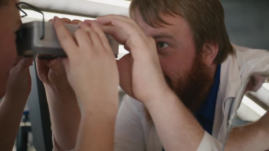 Doctor using a device that the patient holds while observing her eyes