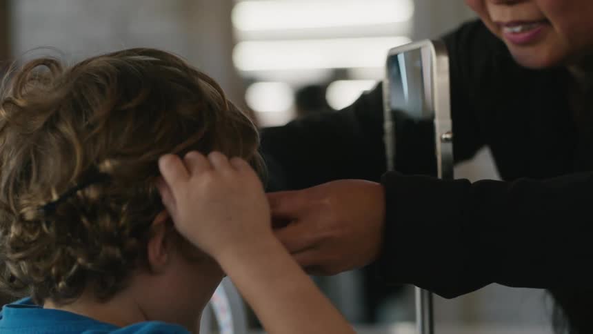 An ophthalmologist helps a boy to try a new pair of glasses