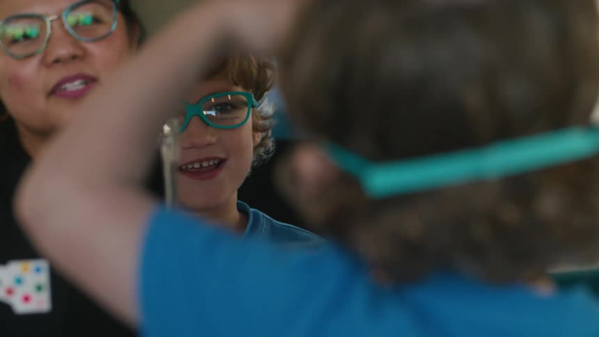A child looking in the mirror excited about his blue glasses