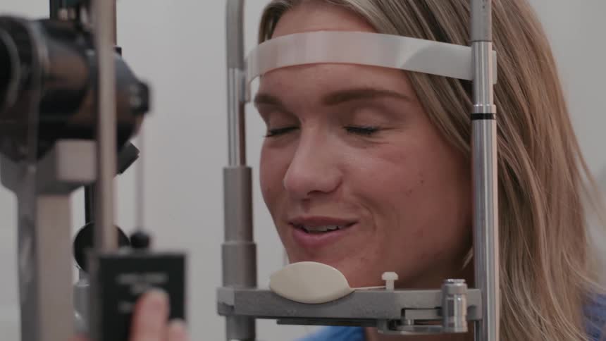 A blonde woman has her face stuck in iron equipment and she is saying something