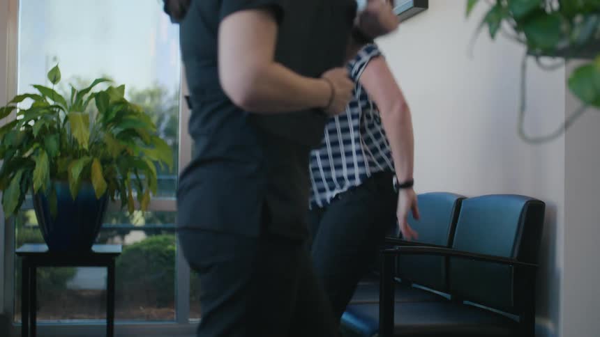A woman and a man are sitting and then someone arrives with a clipboard and talks to the woman and she leaves together