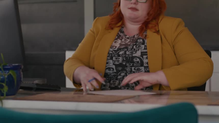 Woman with a pen in her hand sitting at an office desk
