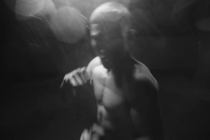 Portrait of a man without a shirt outdoors doing boxing punches in the rain