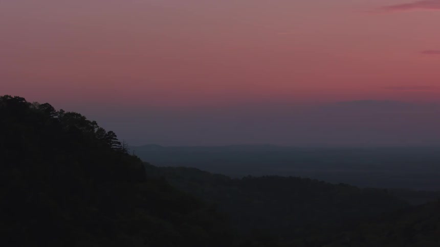 A landscape of a region with hills where the sky is red in the morning