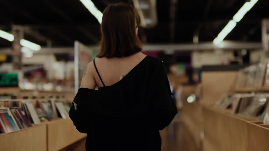 View of a woman from behind walking down the aisle of a vinyl record store