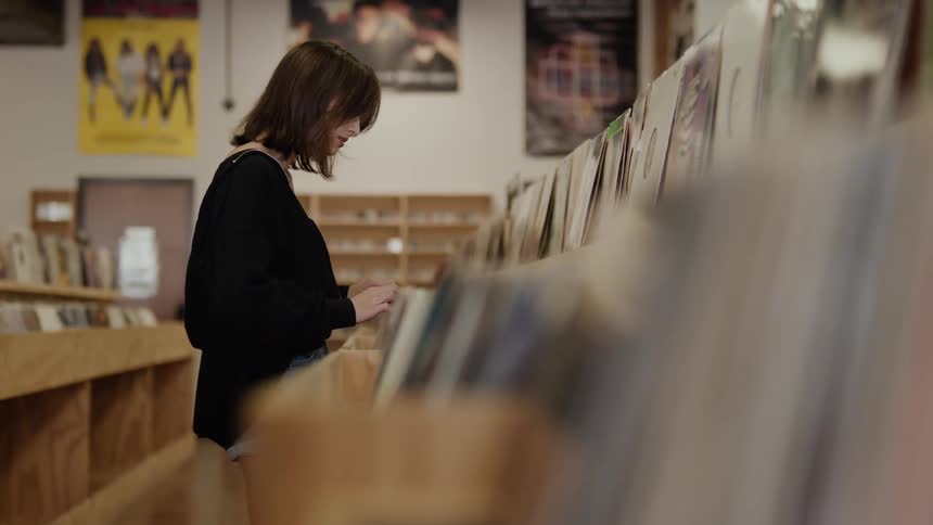 Woman walking down an aisle of a vinyl record store