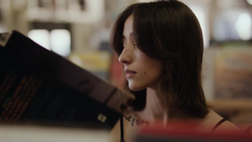 A young woman flips through records reading the back of one