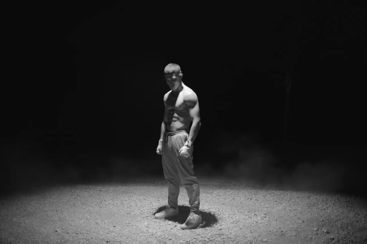 Man without a shirt and boxing gloves in an outdoor location