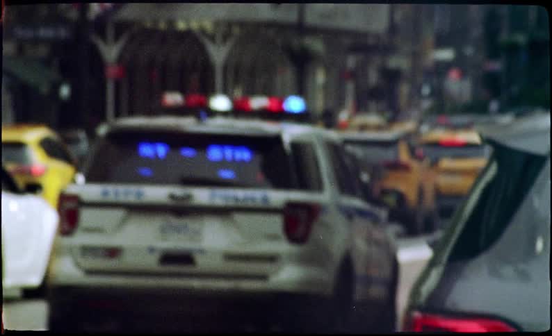 A police car runs with lights on through the city streets
