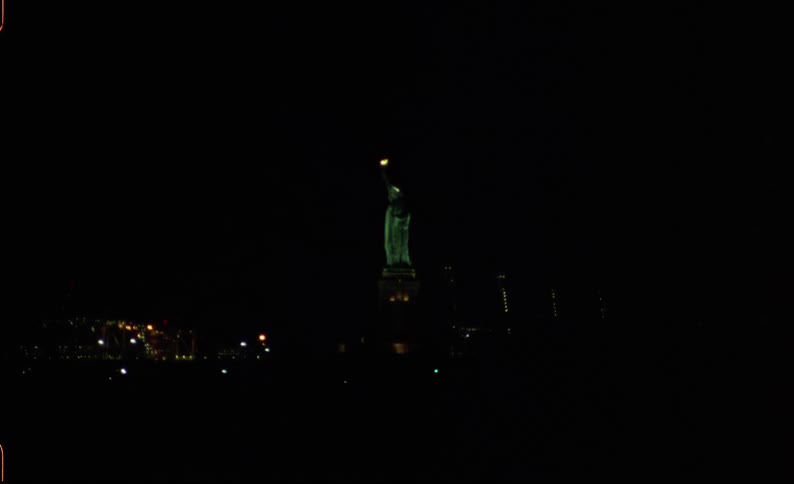 The statue of liberty is lit up at night