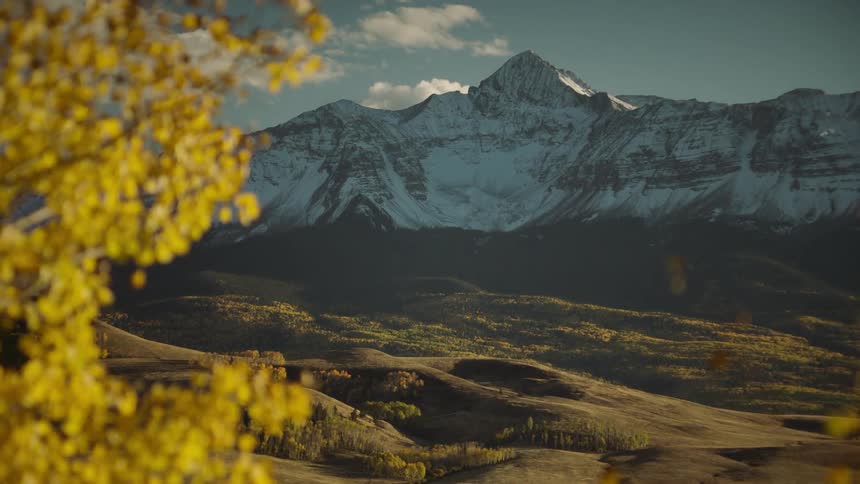 A snowcapped mountain over an autumn landscape with golden foliage