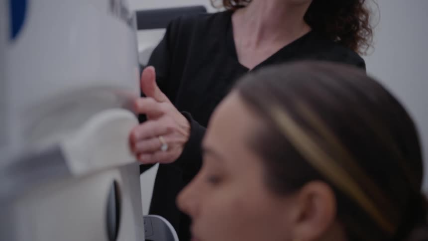 Doctor helping her patient place her eyes on an examination machine