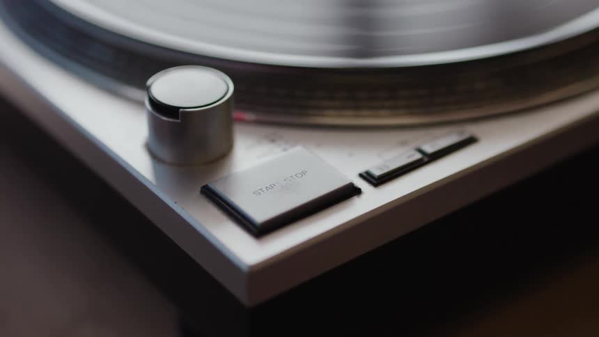 Persons hand turning on a record player