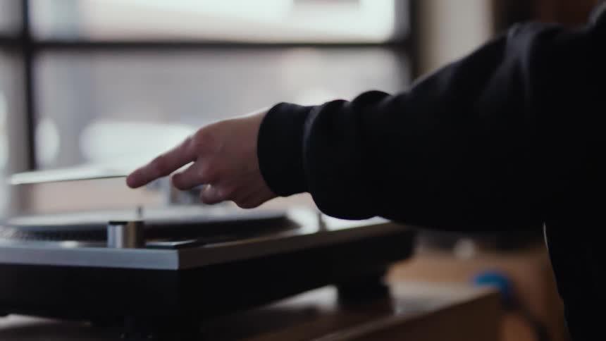 A person placing a vinyl record over a turntable
