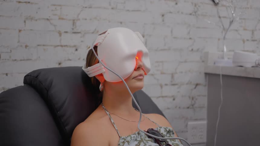 Woman sitting in an armchair with equipment of a face mask with a thread