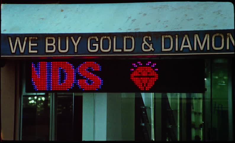 Scrolling sign at a gold and diamond store with cars driving by