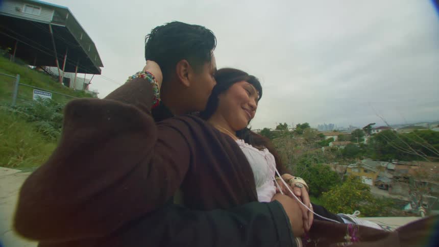 A young happy couple kissing on a hill next to town