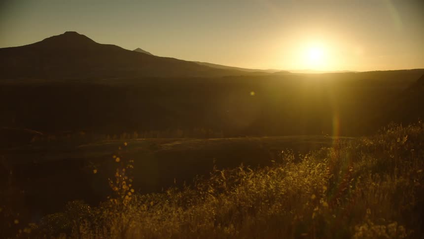 Sunset over a rural landscape with mountain peaks in the horizon