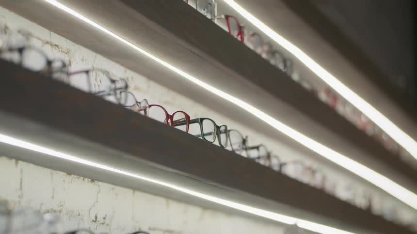 Eyeglasses in various colors for sale showcased in rows with led lighting