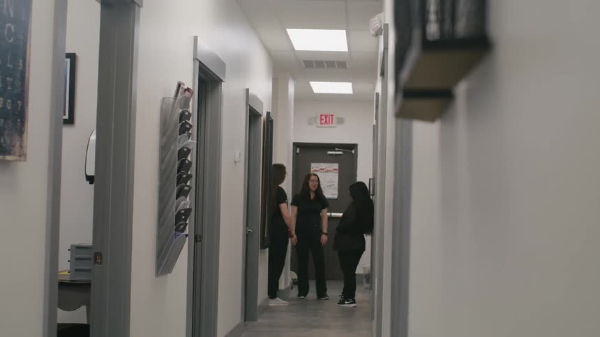 Three healthcare workers talk in a hallway