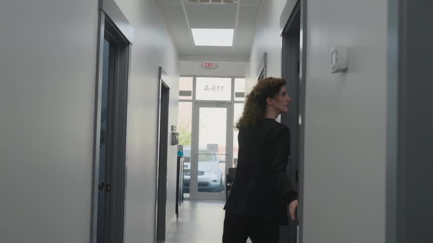 A woman wearing black walking down a corridor